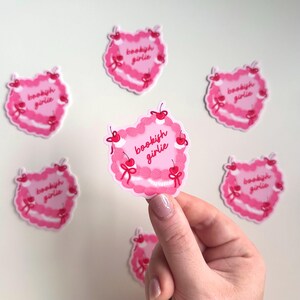 May include: Six pink heart-shaped stickers with the text "bookish girlie" in red lettering. The stickers have a pink and white swirl design and red cherries around the edges.