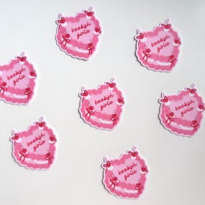 May include: Six pink heart-shaped stickers with the text "bookish girlie" and red cherries around the edge.