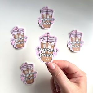 Puede incluir: Cinco pegatinas rosas y blancas con un vaso de café helado de dibujos animados y el texto "caffeine queen" en rosa. Una pegatina está siendo sostenida por una mano.