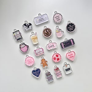 May include: A selection of clear acrylic charms with book-related designs. Charms feature text like "Fantasy Book Club", "Just one more chapter", and "Kindle and bed by 9pm". Other charms depict a gingerbread man, strawberries, and coffee mugs.