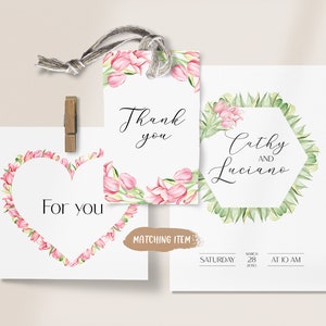 May include: Wedding invitation featuring a floral design. The invitation has a hexagonal frame with green leaves and pink flowers. The text reads "Cathy and Luciano" with the date and time of the wedding below. The invitation also includes a matching thank you tag with pink flowers and the text "Thank you".