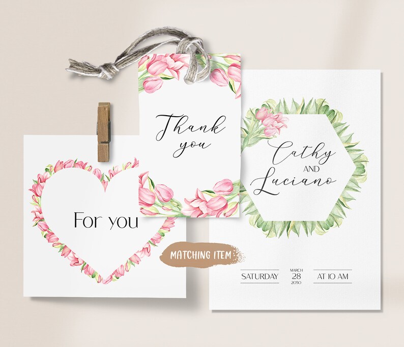 May include: Wedding invitation featuring a floral design. The invitation has a hexagonal frame with green leaves and pink flowers. The text reads "Cathy and Luciano" with the date and time of the wedding below. The invitation also includes a matching thank you tag with pink flowers and the text "Thank you".