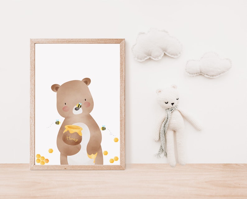 May include: A brown bear holding a honey pot in its paw, surrounded by bees and honeycomb. The bear is looking at the viewer. The image is in a white frame.