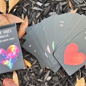 May include: A deck of Love Vibes Oracle cards by Inner Haven Tarot. The black box features a colourful heart design. The cards are grey with a red heart and text that reads "You deserve effort not excuses."