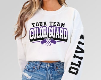 May include: White cropped sweatshirt with black text that reads "Your Team Color Guard" with purple flags. The left sleeve has black text that reads "OLIVITO".