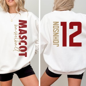 Peut inclure: Sweat-shirt blanc avec un motif rouge "MASCOT basketball" sur le devant et un motif rouge "12 JOHNSON" au dos.