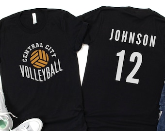 May include: Two black t-shirts. One shirt has a volleyball graphic with the text "Central City Volleyball". The other shirt has the text "Johnson 12" in white.
