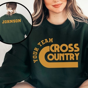 May include: A dark green sweatshirt with the text "YOUR TEAM CROSS COUNTRY" in a gold color on the front. The back of the sweatshirt has the text "JOHNSON" in gold.