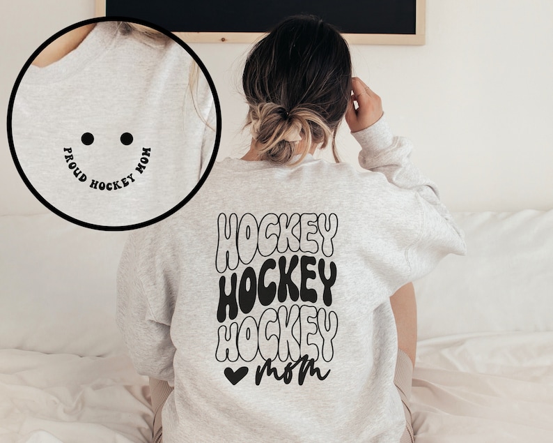 Peut inclure: Un sweat-shirt gris avec les mots "Proud Hockey Mom" en cercle sur le devant et les mots "Hockey Hockey Hockey Mom" en police r&eacute;tro au dos.
