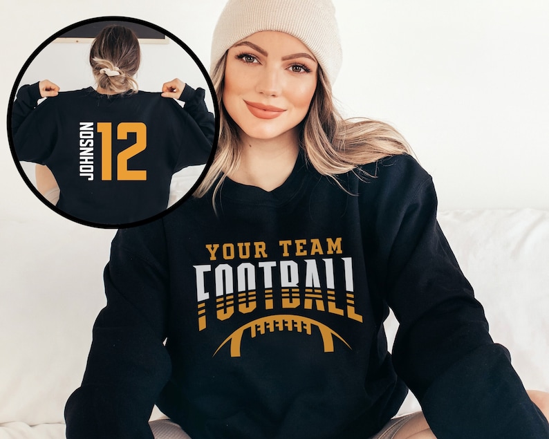 May include: Black sweatshirt with white and gold text that says "Your Team Football" with a football graphic. The back of the sweatshirt has a white number 12 and the text "Johnson" in white.