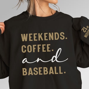 May include: Black sweatshirt with gold text that reads "Weekends. Coffee. and Baseball." The sleeve has a gold number "21" and the name "Johnson" in gold text.