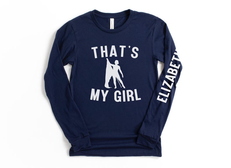 May include: A navy blue long-sleeved t-shirt with white text that reads "That's My Girl" and a silhouette of a woman doing a dance pose. The right sleeve has the name "Elizabeth" printed on it in white.