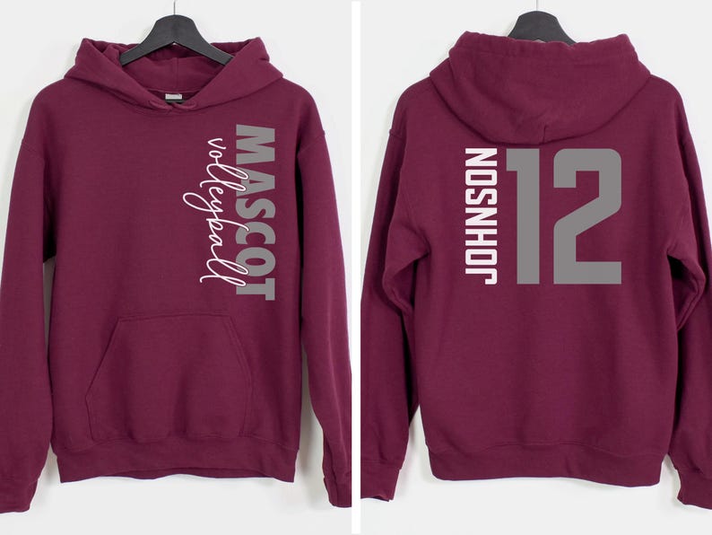 May include: Burgundy hooded sweatshirt with a white graphic on the left side that says "Mascot Volleyball" and a white graphic on the right side that says "Johnson 12".