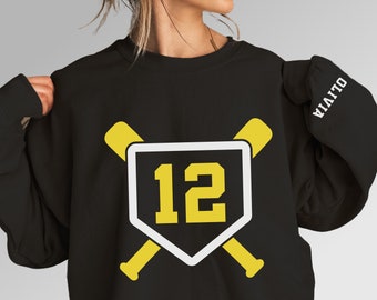 Peut inclure: Sweat-shirt noir avec un losange de baseball blanc et deux battes de baseball jaunes croisées derrière. Le numéro 12 est à l'intérieur du losange en jaune. Le texte "VIAITO" est sur la manche droite en blanc.