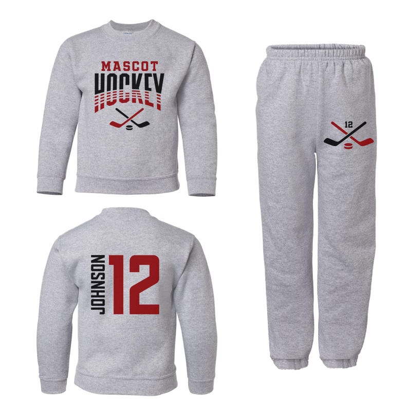 K&ouml;nnte beinhalten: Grauer Pullover mit dem Aufdruck "MASCOT HOCKEY" auf der Vorderseite und einer Grafik mit einem Hockeyschl&auml;ger. Eine passende graue Jogginghose mit einer Hockeyschl&auml;ger-Grafik und der Nummer "12" auf dem Bein. Ein zweiter grauer Pullover mit der Nummer "12" und dem Namen "JOHNSON" auf der R&uuml;ckseite.