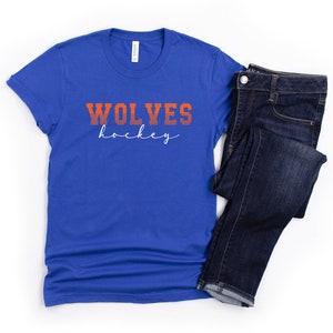 May include: A royal blue t-shirt with the text "WOLVES hockey" in orange and white lettering.