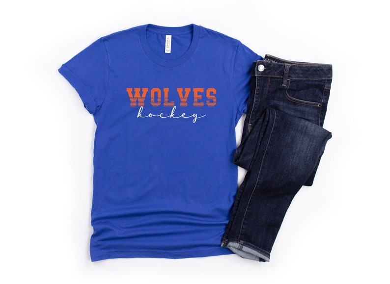 May include: A royal blue t-shirt with the text "WOLVES hockey" in orange and white lettering.