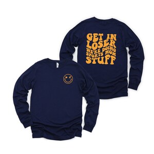 K&ouml;nnte beinhalten: Langarm-Shirt in Marineblau mit einem Smiley auf der Vorderseite und dem Text "Get in loser we're doing sports mom stuff" in Gelb auf der R&uuml;ckseite.