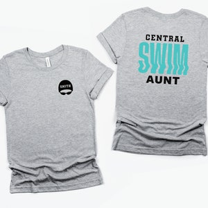 Peut inclure: T-shirt gris avec un graphique de bonnet de bain noir et de lunettes de natation sur le devant et le texte "CENTRAL SWIM AUNT" au dos.