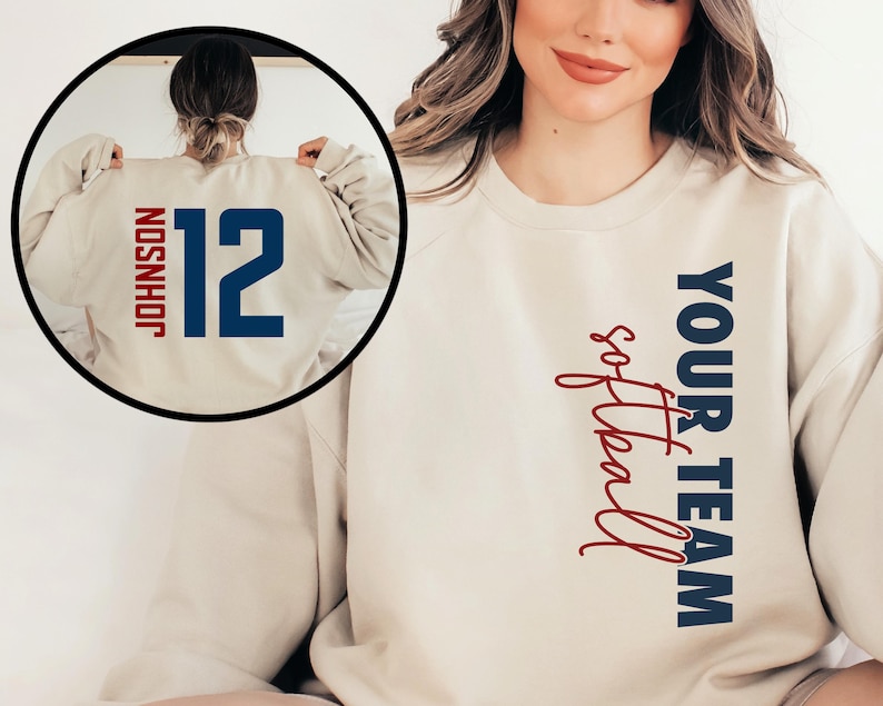 May include: A beige sweatshirt with the text "YOUR TEAM softball" in blue and red on the right side. The back of the sweatshirt has the number "12" in blue with the name "JOHNSON" in blue above it.