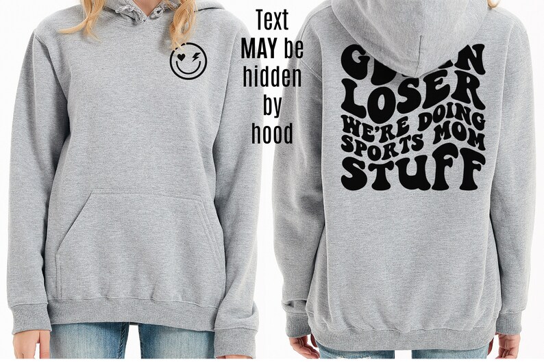 K&ouml;nnte beinhalten: Grauer Kapuzenpullover mit einem schwarzen Smiley-Gesicht mit einem Herz und einem Blitz auf der Vorderseite und dem Text "GIVEN LOSER WE'RE DOING SPORTS MOM STUFF" auf der R&uuml;ckseite.