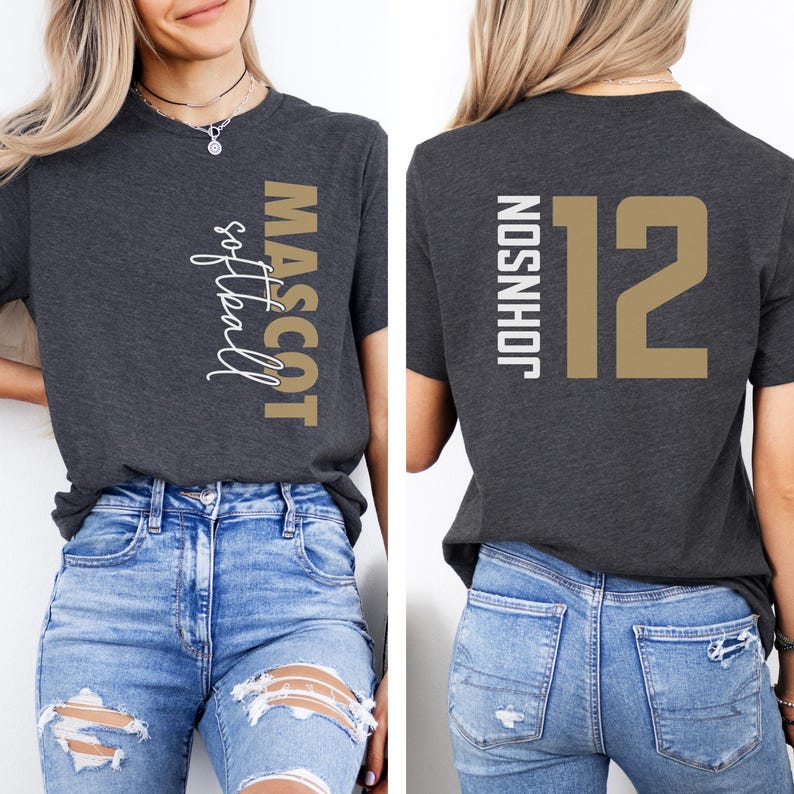 May include: A dark gray t-shirt with a gold and white design. The front of the shirt says "MASCOT softball" and the back of the shirt says "JOHNSON 12".