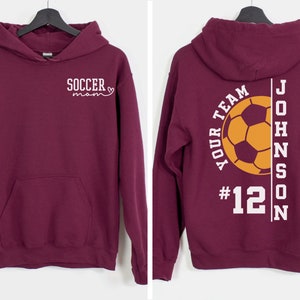May include: Burgundy hoodie with a white soccer mom design on the front and a white soccer design with the text "YOUR TEAM #12 JOHNSON" on the back.