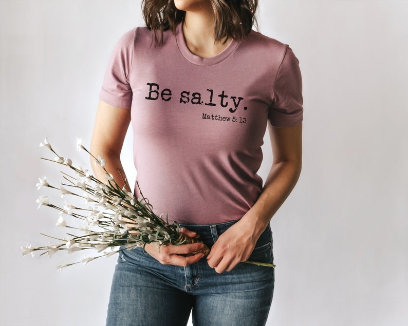 May include: A mauve t-shirt with the text "Be salty. Matthew 5:13" printed in black.