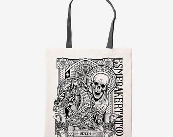 May include: Off-white tote bag with black handles featuring a detailed black and white illustration. The design includes a horse, skull, and ornate geometric patterns. Text on the bag reads "ESMERAKERITATTOO" and "DEATH".