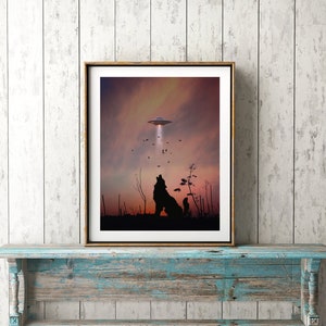 K&ouml;nnte beinhalten: Ein gerahmter Druck eines Wolfes, der zu einem UFO am Himmel heult. Der Wolf ist vor einem Sonnenuntergangshimmel mit ein paar V&ouml;geln, die herumfliegen, silhouettiert.