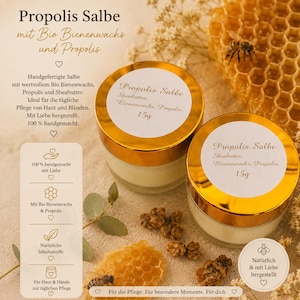 Puede incluir: Dos pequeños frascos de vidrio de Propolis Salbe con tapas doradas, cada uno etiquetado con 15g, Sheabutter, Bienenwachs y Propolis. Los frascos están rodeados de trozos de panal, una pequeña abeja y texto que detalla los ingredientes y su elaboración.