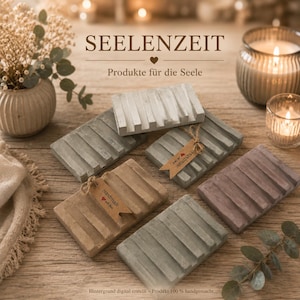 Könnte beinhalten: Eine Sammlung rechteckiger Seifenschalen aus Beton mit erhabenen Rillen in neutralen Tönen wie Grau, Beige und Mauve. Einige Schalen haben kleine braune Papieranhänger mit der Aufschrift Handmade with love an einer Schnur.
