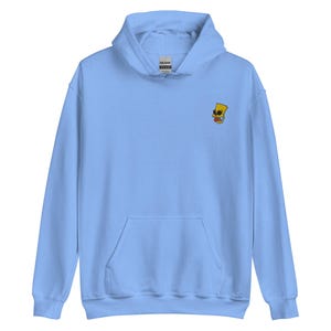 May include: A light blue hooded sweatshirt with a front pocket and a drawstring hood. The sweatshirt features a small embroidered graphic of a cartoon character on the upper left chest. The graphic is yellow, red, and black.