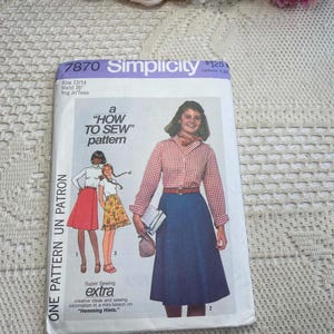 May include: A Simplicity 7870 sewing pattern envelope for a size 13/14, 26 inch waist young junior/teen garment. The cover features illustrations of a person wearing a red and white gingham shirt with a blue skirt, plus two other skirt variations.