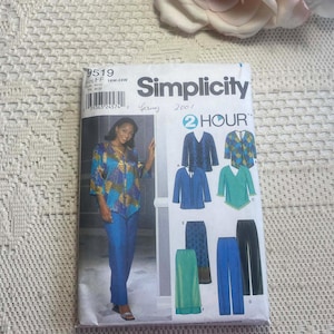 May include: A Simplicity sewing pattern packet showing a woman in a blue and yellow patterned top and blue trousers. The packet includes illustrations of various tops and trousers. A pink rose is in the background.