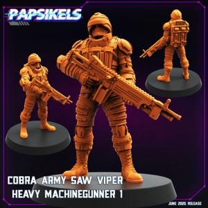 May include: Orange Cobra Army Saw Viper Heavy Machinegunner 1 figurine. The figure is wearing a full body suit and helmet, and is holding a large machine gun. The image includes the text "Papsikels" and "June 2025 Release".