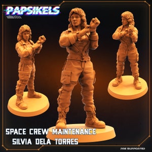 Op de afbeelding: Een 3D-geprint miniatuur van een vrouwelijk personage dat een bruine jumpsuit en een zwart jack draagt. Het personage houdt haar handen in een vechtpositie. Het miniatuur staat op een ronde basis. De tekst "SPACE CREW MAINTENANCE SILVIA DELA TORRES" is onder de basis afgedrukt. De tekst "PRE SUPPORTED" is afgedrukt in de rechterbenedenhoek.