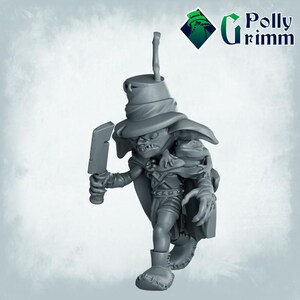 May include: A gray plastic miniature figurine of a goblin wearing a pointed hat and holding a knife. The goblin is carrying a small frog on its shoulder.