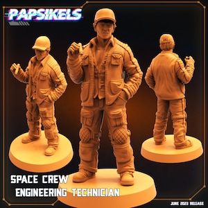 Puede incluir: Una figura miniatura pintada de un miembro de la tripulación espacial que lleva una chaqueta marrón, pantalones vaqueros azules y una gorra de béisbol. La figura está de pie sobre una base redonda. El texto "SPACE CREW ENGINEERING TECHNICIAN" está impreso debajo de la figura.