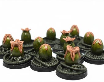 May include: A collection of miniature alien eggs, each with a dark green, oval-shaped body and a light brown, flower-like top. The eggs sit on a dark, textured base, creating a sci-fi or fantasy theme.