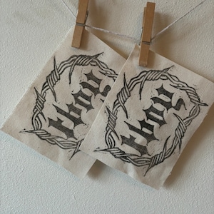 May include: Two white fabric patches with black barbed wire designs and the word "HATE" printed in black gothic lettering.