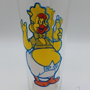 May include: A clear glass tumbler featuring a colorful graphic of a cartoon duck wearing a bonnet, a bow tie, and a diaper, while holding a baby bottle. The character is rendered in yellow, red, and blue outlines. The text BIG BABY is visible at the base.