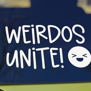 May include: White vinyl sticker with the text "Weirdos Unite!" and a cartoon smiley face with wide eyes and a big smile.