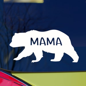 May include: White vinyl decal of a bear silhouette with the word "MAMA" inside. The decal is on a blue car window.