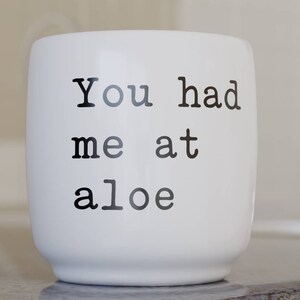 May include: White ceramic mug with black text that reads "You had me at aloe".