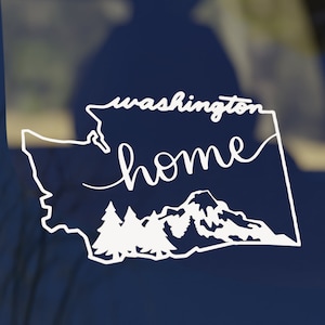May include: White vinyl decal of the state of Washington with the words "Washington home" and a silhouette of mountains and trees inside the state outline.