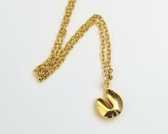 May include: A gold chain necklace with a gold fortune cookie pendant.