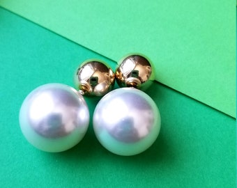 May include: A pair of gold and white pearl earrings. The earrings have a large white pearl on one side and a smaller gold ball on the other side.