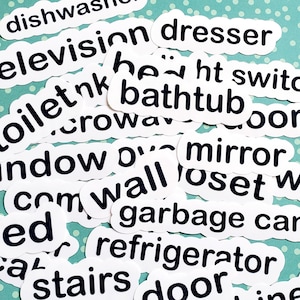 May include: White paper labels with black text listing common household items, such as "television", "dresser", "bathtub", "toilet", "window", "mirror", "closet", "bed", "refrigerator", "door", "cabinet", "garbage can", "stairs", "dishwasher", and "light switch".