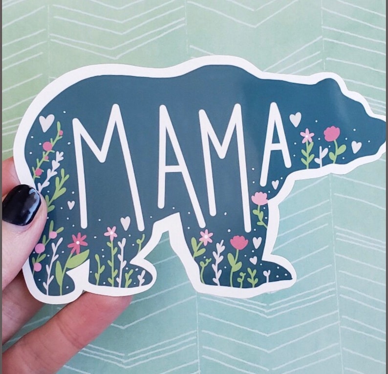 May include: A blue bear silhouette with white floral accents and the word "MAMA" in white lettering.